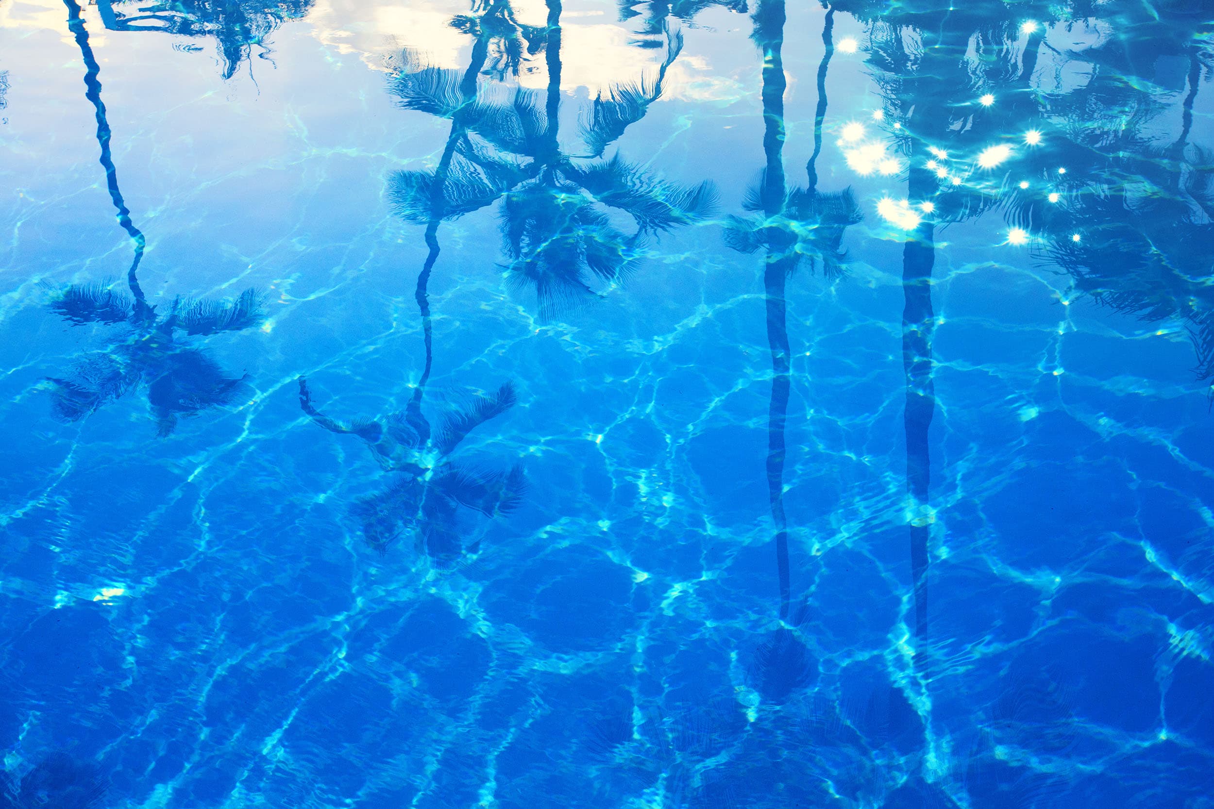 Crystal clear pool water with palm reflections